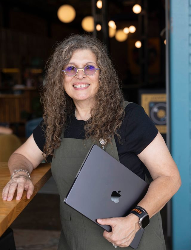 Nanette standing holding her laptop